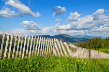 Wooden fence on top of mountains, bright blue sky. Ukraine, Carpathians.