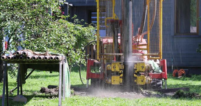 Drilling in ground for artesian well for a clean water supply. Water shooting out of tube while drilling and putting in a metal tube.