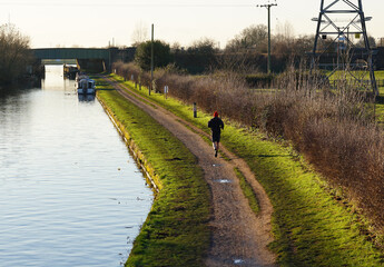 Lone jogger on a canal towpath
