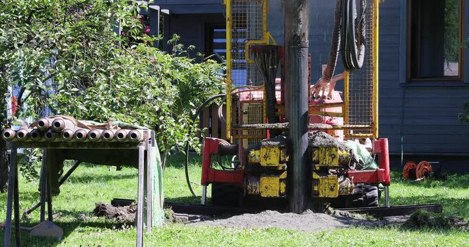 Drilling in ground for artesian well for a clean water supply. Water shooting out of tube while drilling and putting in a metal tube.
