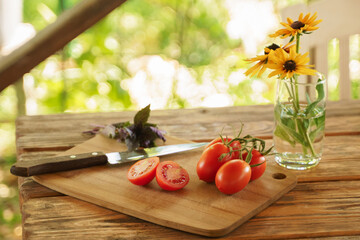 Basil, tomatoes on a branch, a cut tomato and a knife][
