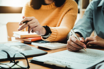 focus consultant holding a pen and the business owner holding a pen reading the terms of a joint...