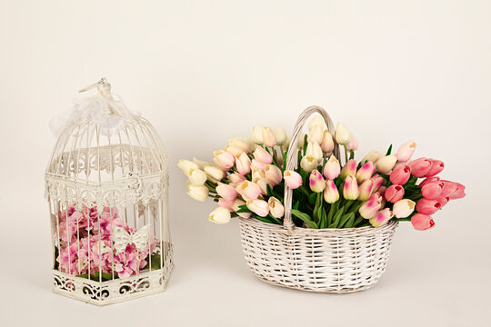 Cesta de mimbre con tulipanes rosas y jaula para decoraci&oacute;n.