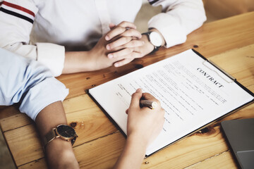 Business owner holding a pen to read the conditions to enter into a joint venture contract with a...