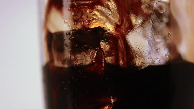 A close-up of coffee poured over ice and milk or cream being poured into the glass