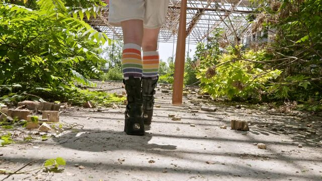 Foot punk teenager girl style in rude high boots and striped stockings walks along roof of abandoned building Slow motion Woman. Alternative in youth. Hipster, frick, grunge