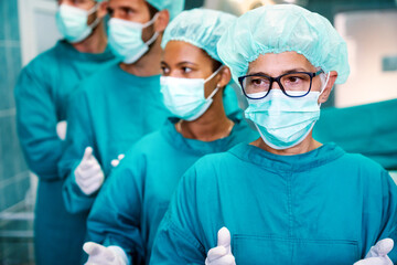 Fototapeta na wymiar Successful team of surgeon standing in operating room, ready to work on a patient