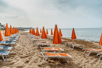 View of umbrellas,deck chairs on sandy beach and sea.Empty beach waiting for tourists, Sicily, Italy.Travel agency concept banner.Relax vacation luxury copy space.Group tours on summer holiday