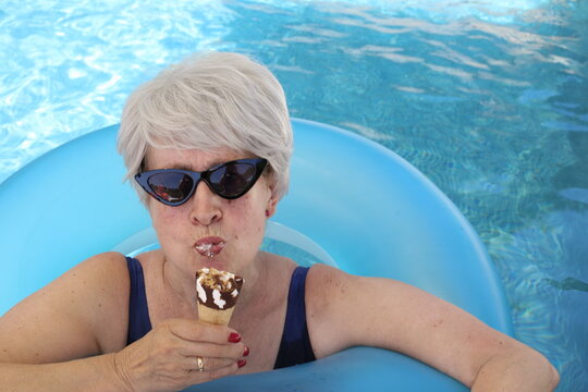 Senior Woman Eating An Ice Cream In Swimming Pool