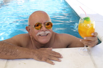Senior man drinking cocktail in swimming pool