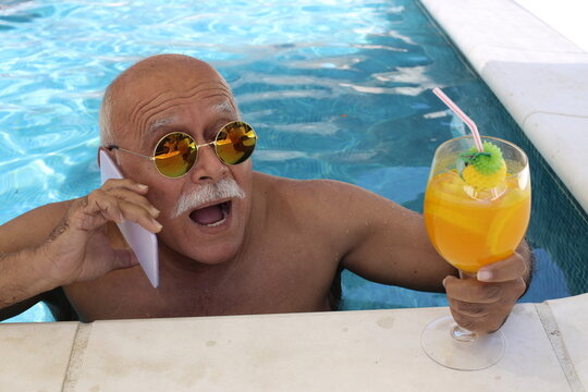 Surprised senior man in swimming pool drinking cocktail - Powered by Adobe