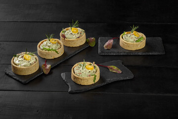 Shortbread tartlets with filling of guacamole, shrimps, herbs and kumquat
