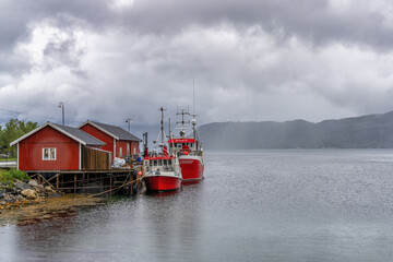 fishing boats and colorful red houses in the harbor of Kilboghavn on the Helgeland coast of...