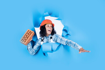 going to throw it. girl builder in hard hat on construction site. engineer hold brick. young female...