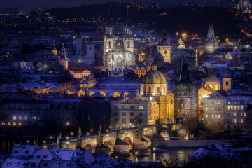 View of the centre of Prague and Charles Bridge, Old town Square and Tyn temple in the evening with night illumination in winter. Tourism. Towers of Prague. Czech Republic. Snow.