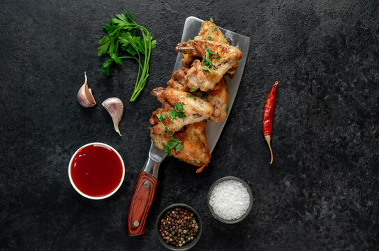 grilled chicken wings on a knife on a stone background