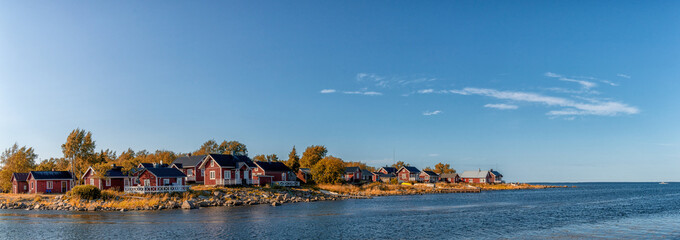 idyllic Baltic Sea panorama landscape with red cottages on the shoreline under a blue sky in autumn