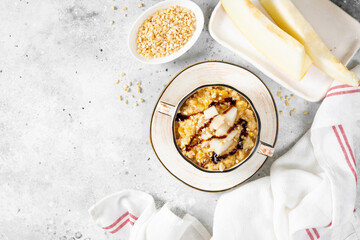 Millet porridge with melon slices and walnuts in a ceramic bowl on a light gray kitchen table top view from a copyspace. Delicious and healthy breakfast