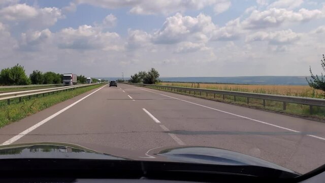 POV driver view through car windshield while fast driving by road with bad tarmac and pits. Car traffic on highway E95 needs to road renovation