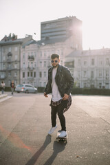 Hipster man in the city portrait wearing glasses skateboarding