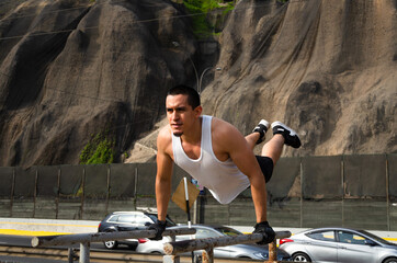 Handsome man exercising on parallel bars on the street outdoors