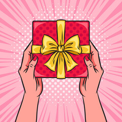 Hands holding red gift box or present with a bow and ribbons. Pop art vector comic illustration. Top view.
