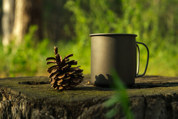 Titanium cup and a pine cone stand on a stump in a forest