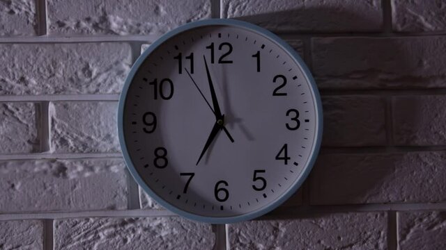 The Time On The Clock Seven. Round office clock showing seven o.Clock With The Black Arrow Running In The Background Of The Arabic Numerals..