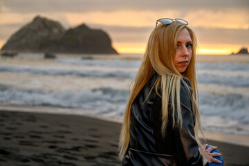 Bright portrait of an attractive blonde woman smiling conservatively by the ocean somewhere at the shores of Northern California