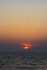 Fototapeta na wymiar Ein Sonnenuntergang und ein Flugzeug am Meer in der Nähe von Rom, Italien