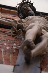 Holy cross with crucified Jesus Christ. Bottom view of an ancient statue. Vertical image. Selective focus on eyes.