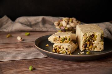 Organic halva with pistachios on a wooden surface. Traditional middle eastern sweets. Jewish, turkish, arabic oriental national dessert. Turkish delight concept. Natural vegan product. Copy space.