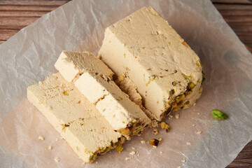 Organic halva with pistachios on a wooden surface. Traditional middle eastern sweets. Jewish, turkish, arabic oriental national dessert. Turkish delight concept. Natural vegan product. Copy space.
