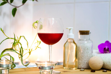 Spa-beauty salon, wellness center. Spa treatment aromatherapy for the female body in the bathroom with a glass of wine, with candles, oils and salt