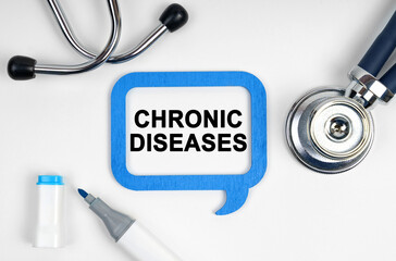 On the table is a stethoscope, a marker and a sign with the inscription - CHRONIC DISEASES