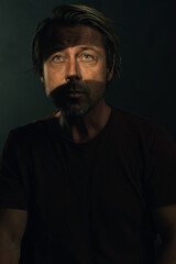 Fototapeta premium Dark mysterious portrait of a blond man with light blue eyes and