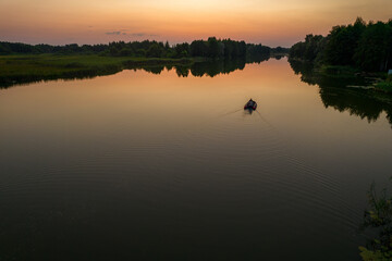 Aerial view of a fishing boat on the river at sunset
