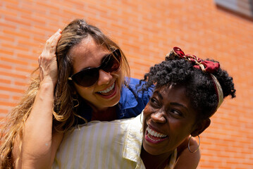 Cheerful black woman giving piggyback ride to girlfriend