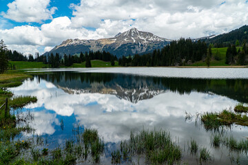Lauenensee in Gstaad with a beautiful reflection of the cloudy sky in Swiss alps