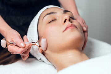 Cosmetologist making face therapy for rejuvenation to woman while lying on a stretcher in the spa center.