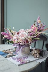 Bouquet with roses, hydrangea and a and dry lagurus. Stabilized flowers in pink color in a ceramic vase at home on the dressing table.
