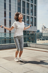 Happy mature female with skipping rope outdoors