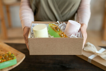 Hands of young woman packing bars of fresh handmade natural soap into giftbox