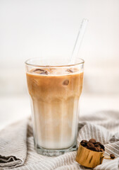 Iced latte coffee drink in tall glass with glass straw