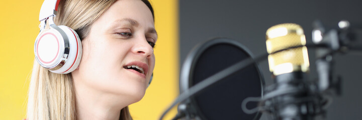 Portrait of singing woman in headphones in front of microphone