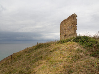 Fototapeta na wymiar Vistas de las ruinas de la Torre de San Telmo en los acantilados de la Ensenada de Santa Justa, con un horizonte nuboso en Cantabria, España, verano de 2020.