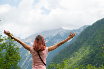 Young woman standing outside in green nature looking at mountains