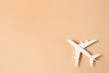 Flat lay design of travel concept with plane on brown background.