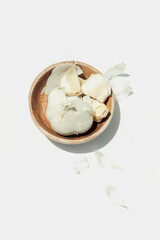 Garlic clove in shallow wooden bowl on white background