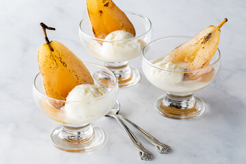 Close up of glass dishes filled with poached pears served with ice cream.